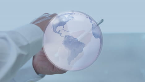 animation of grey globe over hands of businessman using smartphone