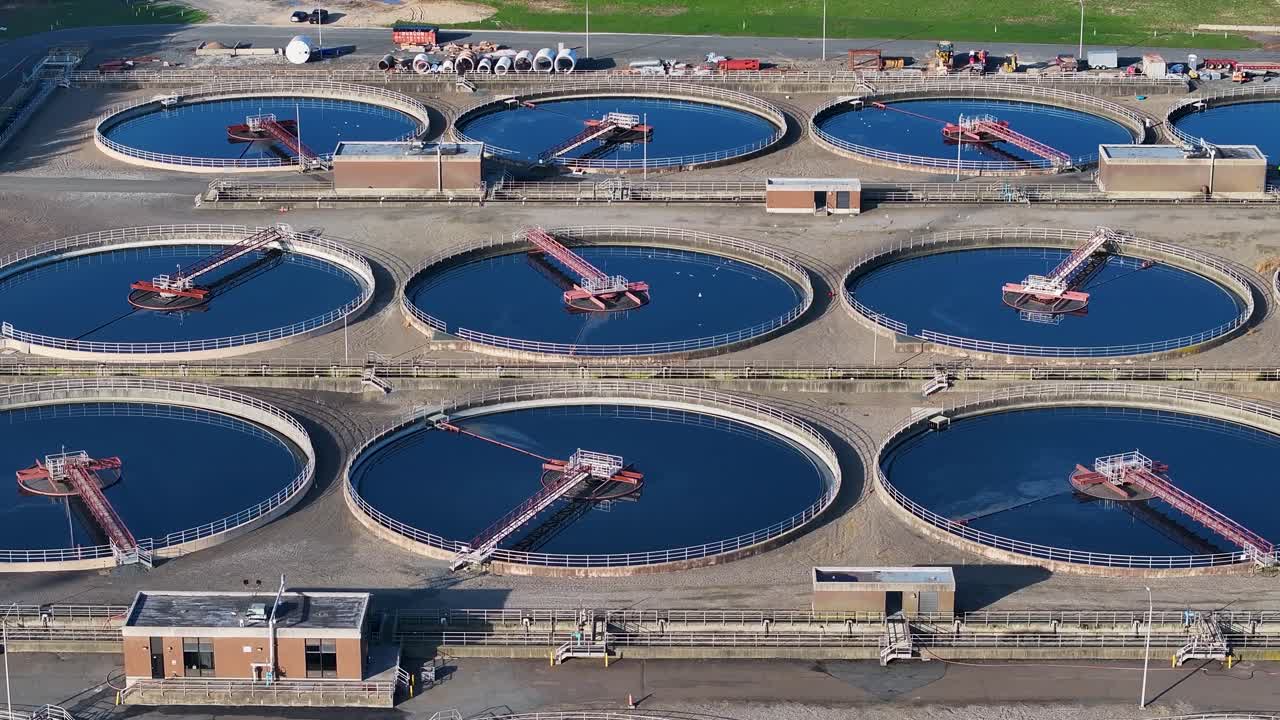 Sideways aerial view of large wastewater treatment plant with several tanks
