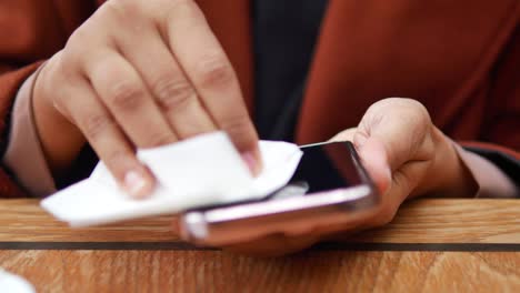 una mujer limpiando su teléfono con una toalla
