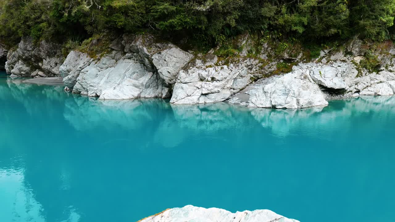 Rocks mirrored in the clear waters of Hokitika Gorge, a mesmerizing display of nature's reflection