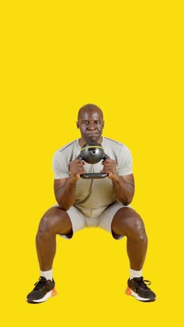 man performing a dynamic kettlebell exercise on a yellow background