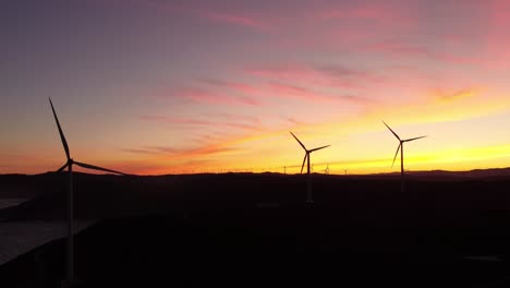 silhueta de fazenda de turbina eólica durante o céu colorido ao pôr do sol