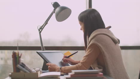 young woman sitting at her desk she's drawing writing and using pen with digital tablet computer. hands with pen