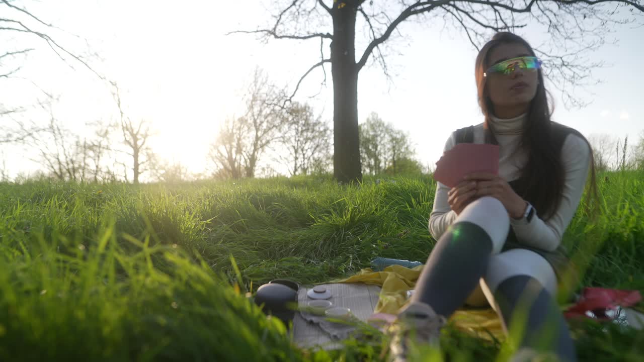 Kvinde nyder en picnic i en park ved solnedgang