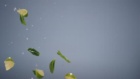 prise de vue super lente de feuilles de citron vert et de menthe fraîchement tranchées volant contre un fond lumineux. prise de vue avec une caméra vidéo à grande vitesse