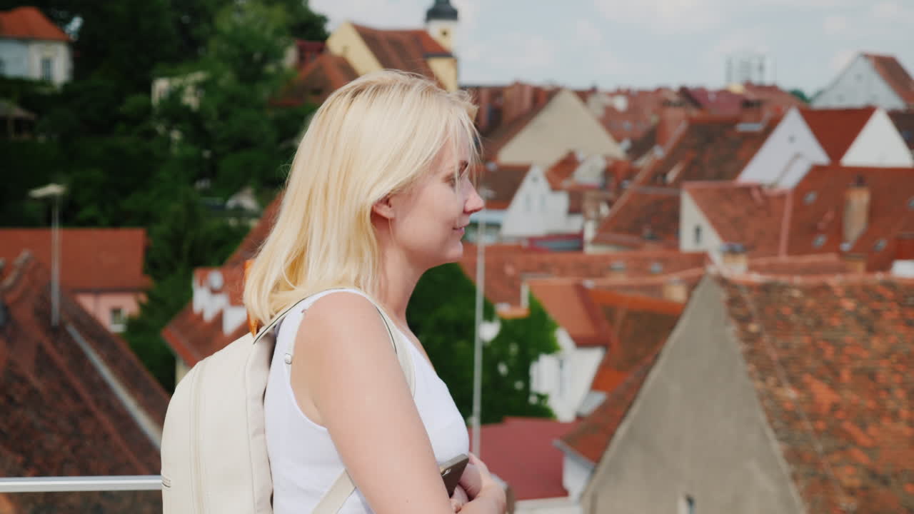 젊은 여성 관광객이 높이 2에서 오래된 유럽 도시를 감상하고 있습니다.