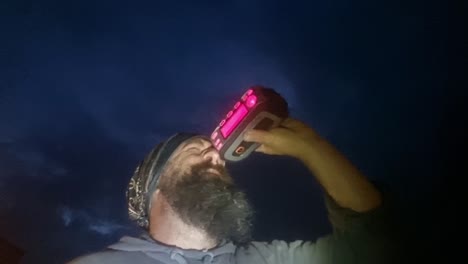 Curious-bearded-male-searching-stars-with-electronic-star-finder-telescope-looking-up-at-clear-night-sky