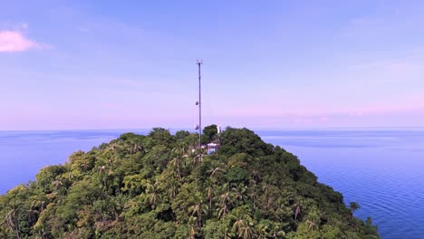 cell tower and light house on a hill with sea in the background