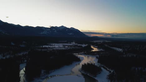 Inauguración-Aérea-Del-Hermoso-Paisaje-Invernal-Durante-La-Hora-Dorada:-Vista-De-Pájaro-Del-Río-Reflectante-Y-Majestuosas-Montañas-En-Columbia-Británica,-Canadá