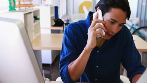 Male-executive-talking-on-mobile-phone-while-working-at-his-desk-4k