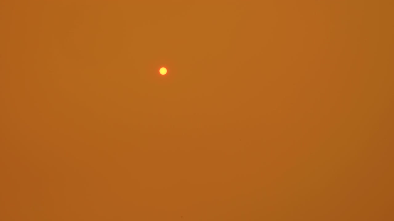 Oranje zon in rokerige oranje lucht