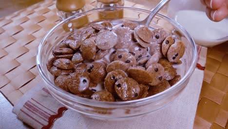 copos de chocolate crujientes en un tazón para un delicioso desayuno matutino con leche. cámara lenta con toma de seguimiento de rotación.