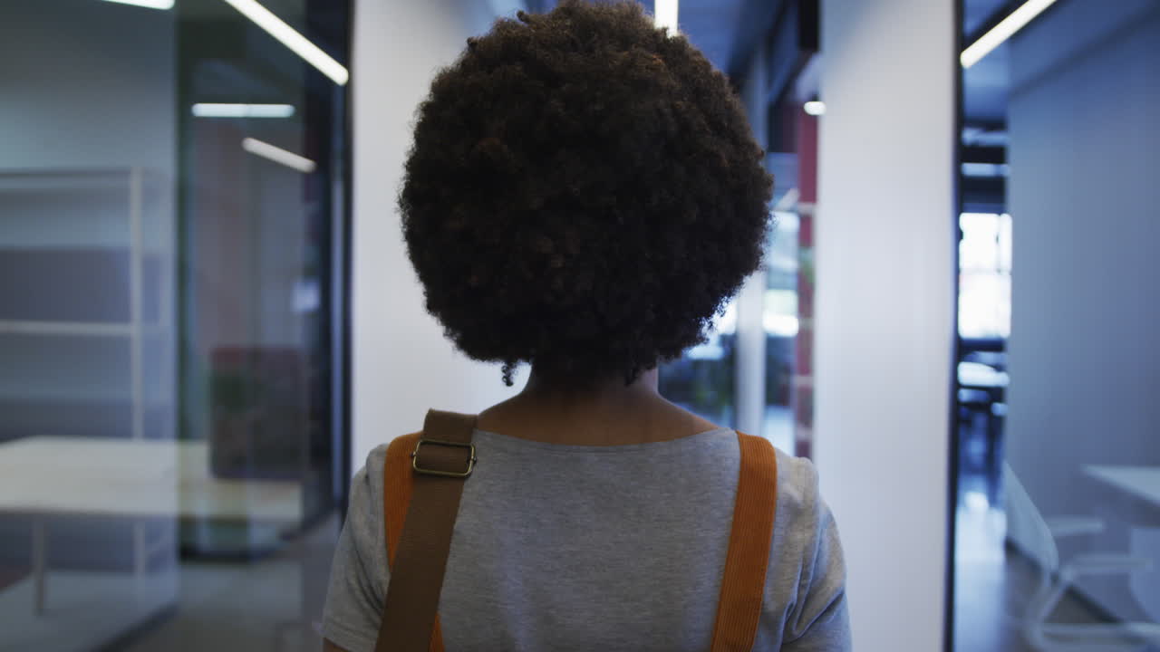 Biracial businesswoman walking and drinking a cup of coffee in modern office