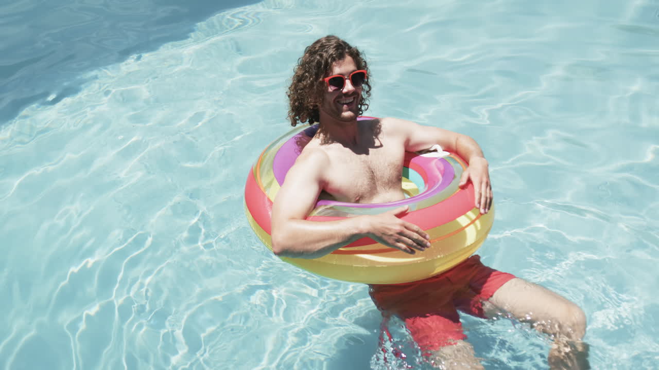 Young Caucasian man enjoys a sunny day in the pool, with copy space