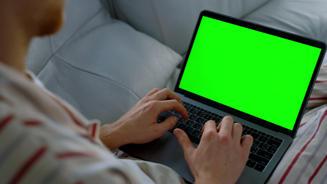 Man surfing chroma key laptop at home office. Unknown busy student writing essay