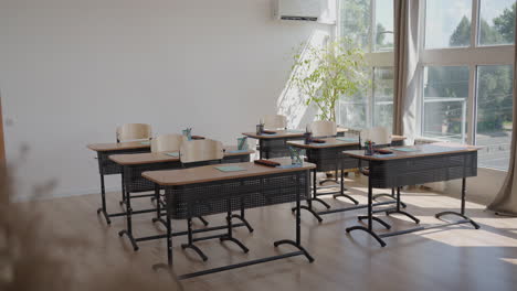 Rays-of-light-falling-to-the-empty-dark-classroom.-The-camera-panning-behind-rows-of-desks-and-chairs.-Teaching-class-without-students-during-a-break.-Abandoned-school.-Disturbing-mood.