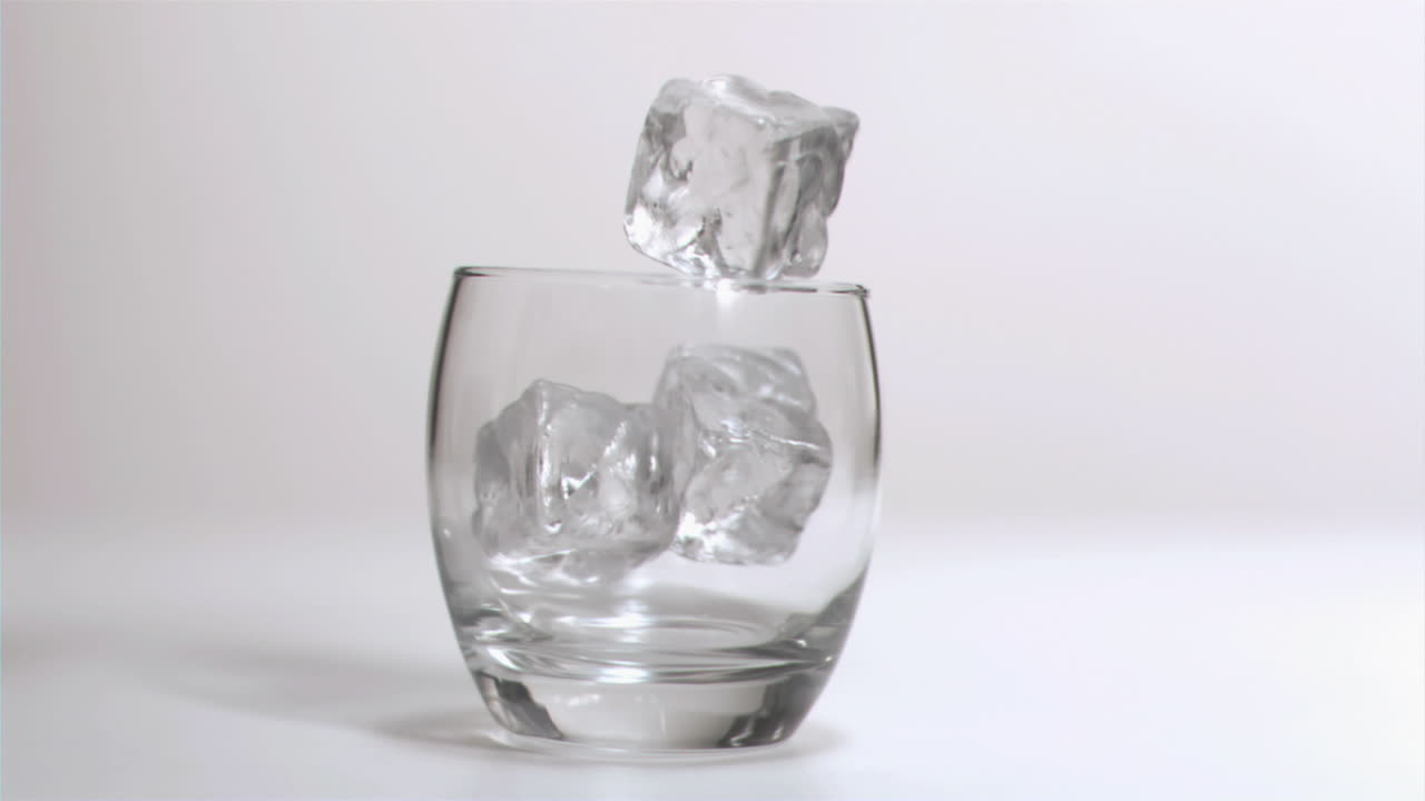 cubos de hielo cayendo en súper cámara lenta en un vaso