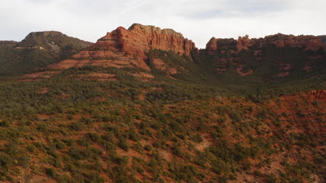 aerial: rock mountain valley with cloudy sky at sedona, arizona - drone flying backward shot