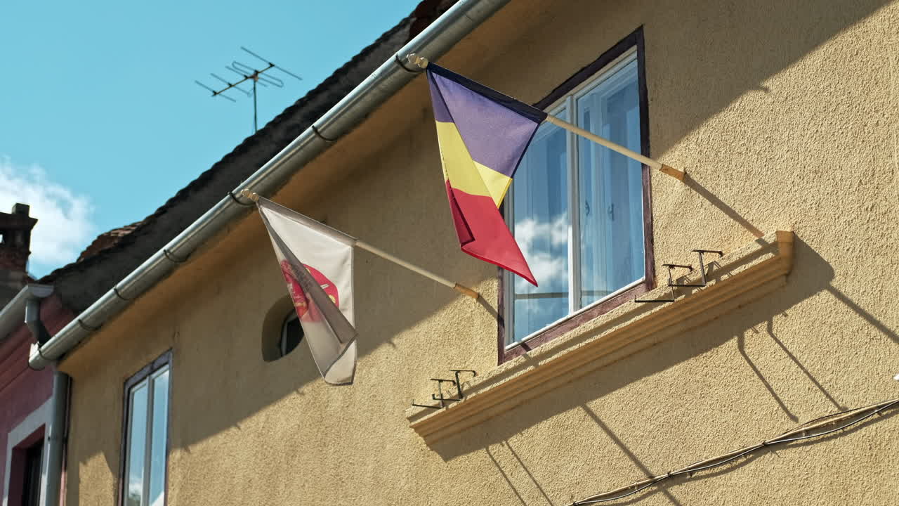 Facade of a building with national and other flags in a town, Romania