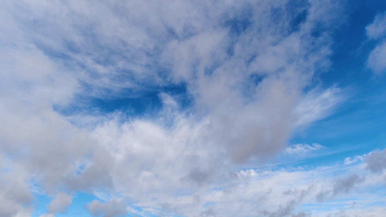 Blue sky and clouds drifting in different directions