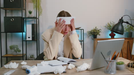 sick ill businesswoman in suit suffering from cold flu or allergy working on laptop at home office