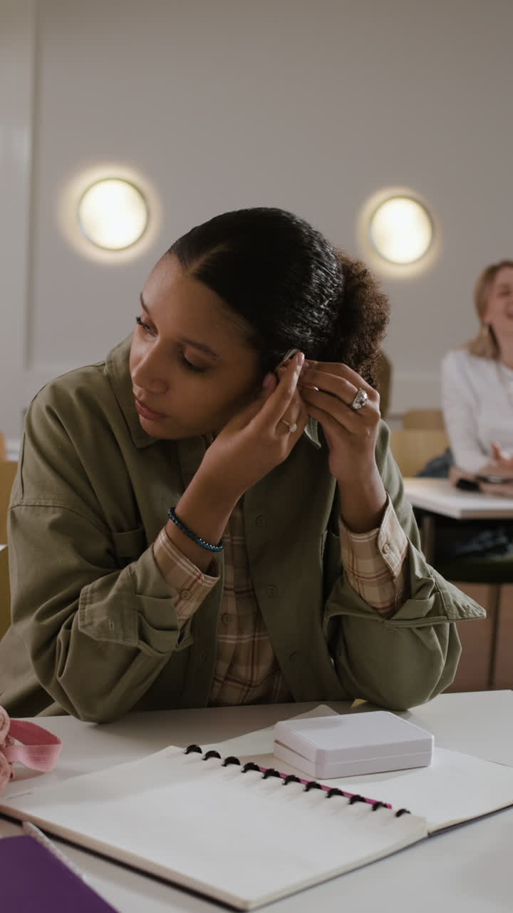 A student putting on her earrings in the classroom