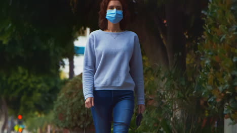 [Camera-Used:-Canon-C300]-Caucasian-woman-wearing-a-surgical-face-mask-while-outside-walking-her-dog