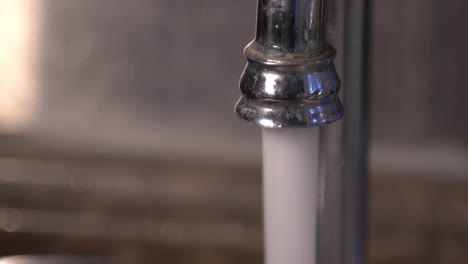 water flowing out of the water tap into the kitchen sink