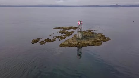 Aerial-Float-away-from-Vanderbilt-Reef-and-Navigation-Beacon-as-Seagull-Flies-Away,-Ocean-and-Alaska-Mountains-Behind