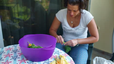 imágenes de una mujer caucásica preparando y limpiando flores de calabacín al aire libre