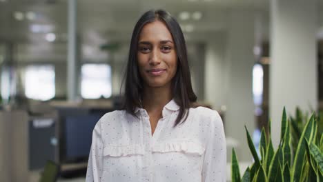 Video-of-happy-biracial-woman-looking-at-camera-in-office