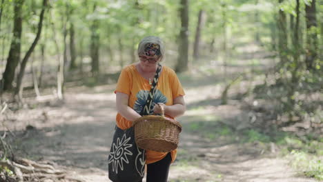 Plano-Medio-De-Ancianas-Gordas-Con-Cabello-Gris-Y-Camiseta-Naranja-Mirando-La-Canasta-De-Madera-En-Medio-De-Un-Bosque-Verde-Durante-Un-Día-Soleado-En-Cámara-Lenta-Con-Fondo-Borroso