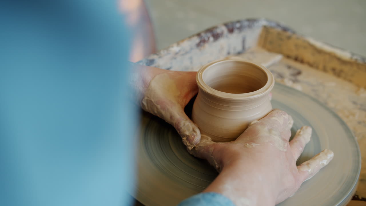 mujer moldeando arcilla en la rueda de cerámica