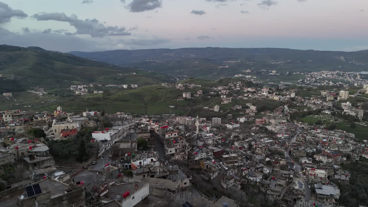 Prospettiva aerea da drone di un villaggio remoto immerso tra le verdi colline e valli della campagna siriana