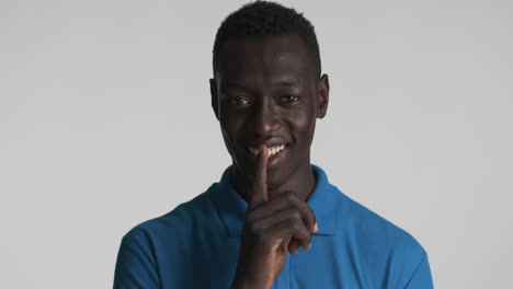 un hombre afroamericano sonriente sobre un fondo gris.