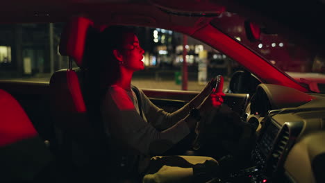 woman driving car at night in the city