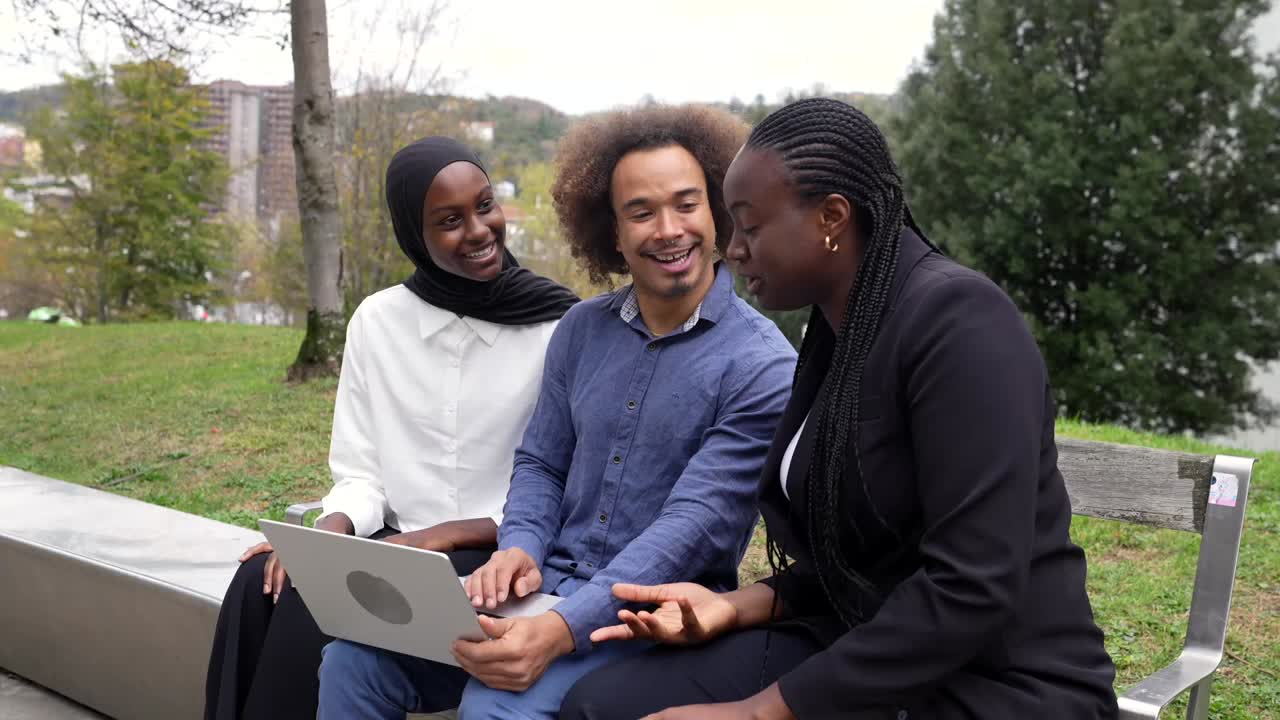 Diverse group of people collaborating on a laptop in a park