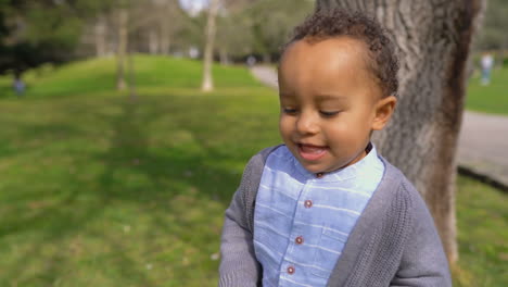 boy playing hide-and-seek, smiling, running away from tree