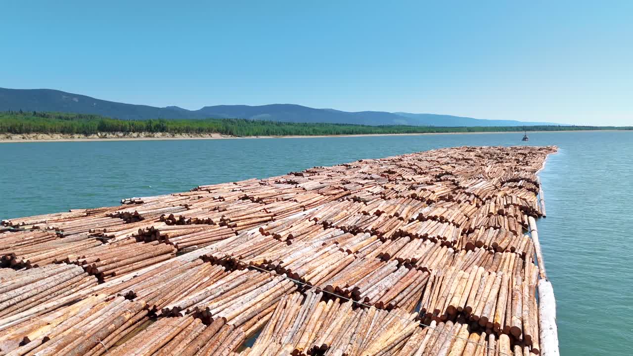 Explore the Canadian wilderness through drone footage of a logging raft and tugboat transporting lumber, showcasing the economic impact of the construction and logging industry.