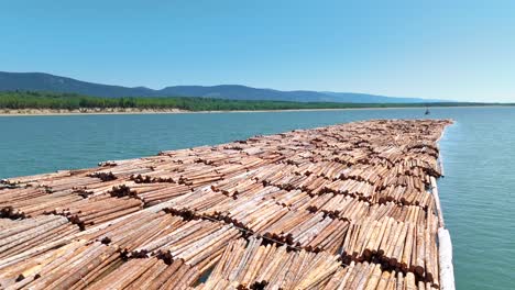explore the canadian wilderness through drone footage of a logging raft and tugboat transporting lumber, showcasing the economic impact of the construction and logging industry.