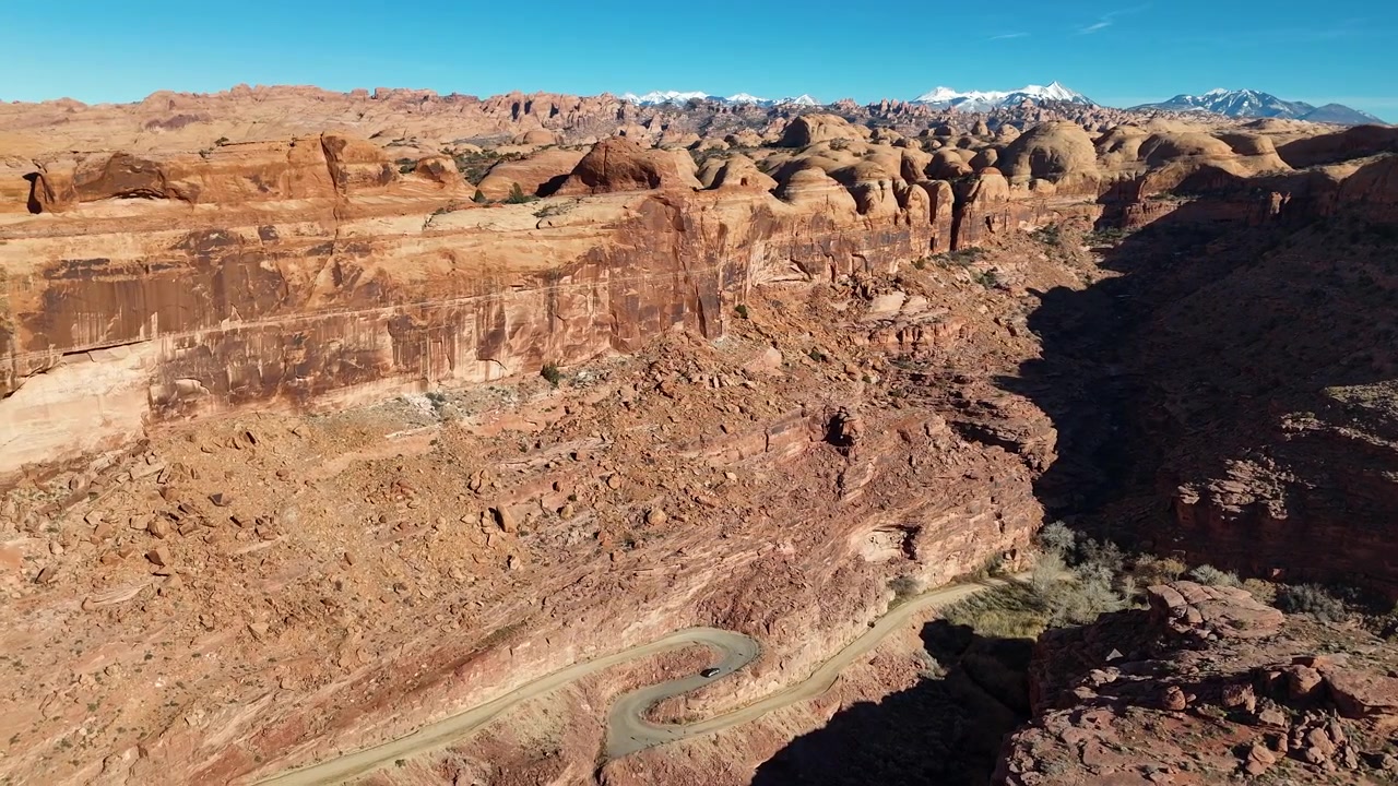 Ripresa aerea con drone di una strada fuori Moab, USA, percorso panoramico sotto le scogliere di arenaria nel deserto dello Utah