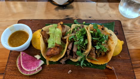 Zoom-in-shot-of-delicious-tacos-and-a-dipping-sauce-served-on-a-banana-leaf