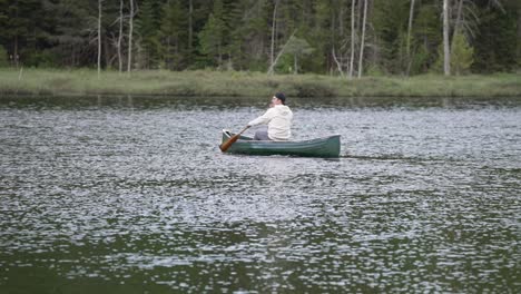 man canoeing on serene lake at forest resort of le vertendre in quebec, canada