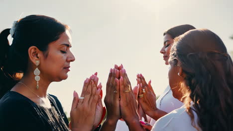 women practicing meditation at sunset by the ocean