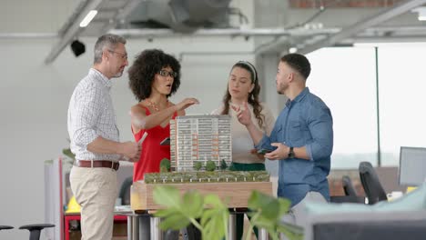 equipo de diversos arquitectos discutiendo sobre un modelo de edificio 3d en la oficina