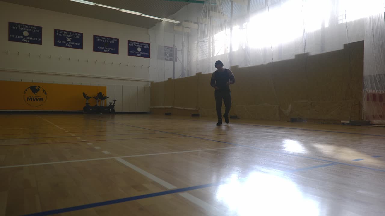hombre caminando desde la pared cruzándose a sí mismo - hombre negro musculoso atlético fuerte parado en la cancha de baloncesto mirando alrededor en 4k
