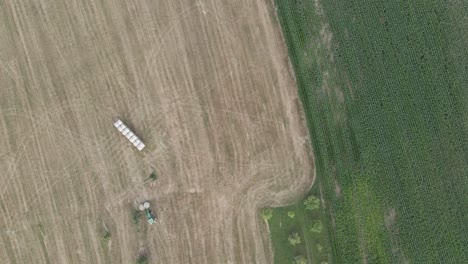 toma aérea superior de un tractor depositando una bala de heno en un campo en francia