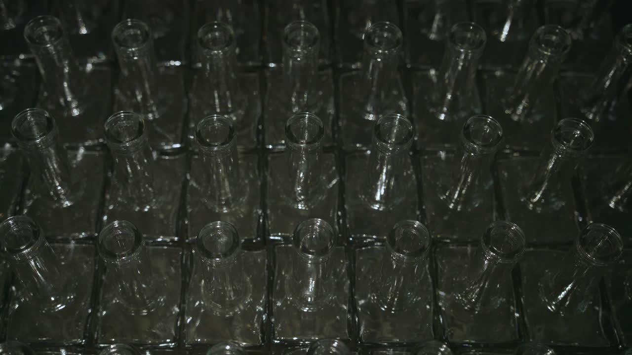 Plan fixe de bouteilles d'alcool vides éclairées par une lumière balayante.