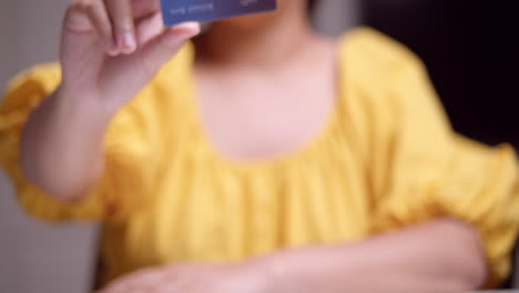 a woman showing a close-up shot of a credit card that she is holding with her fingers on her right hand