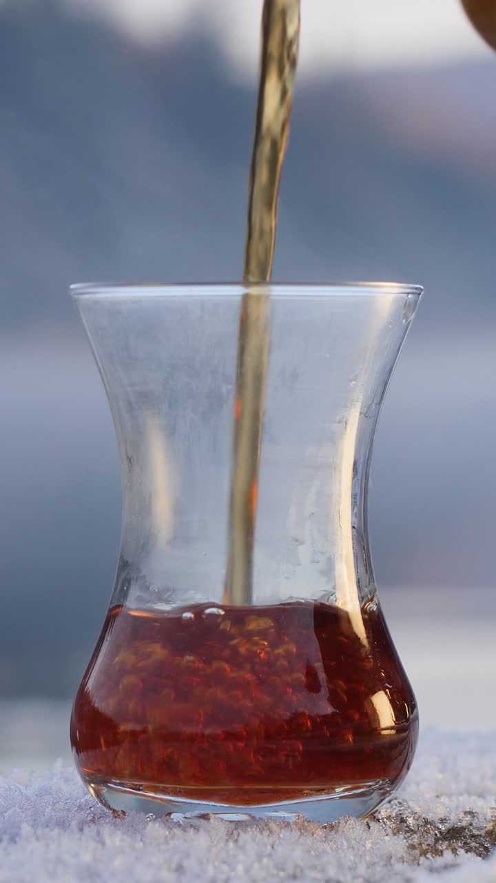 pouring black chai (tea) into curved glass frosty morning